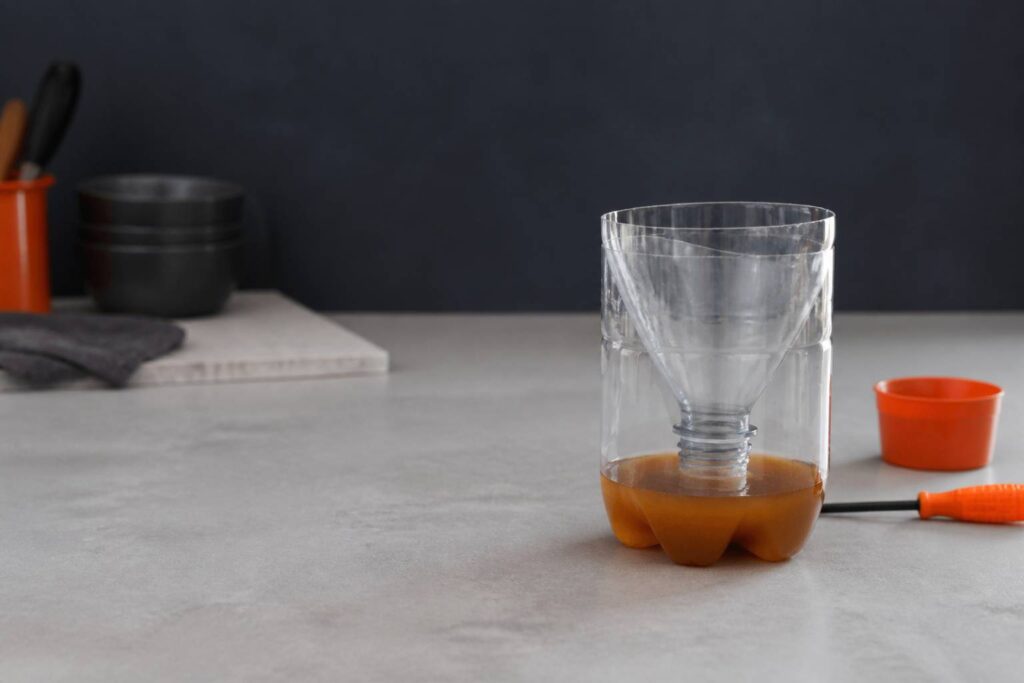 Piège à mouches artisanal en bouteille plastique coupée en entonnoir sur un plan de travail