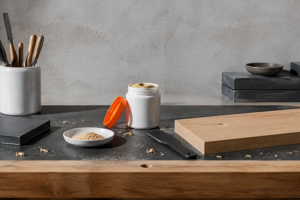 Pot de pâte à bois maison et sciure fine sur un établi de bricolage rangé avec une spatule
